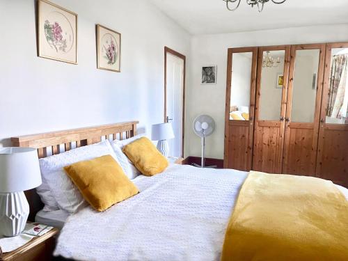 um quarto com uma cama grande e almofadas amarelas em Home Farm Cottage em Barnstaple