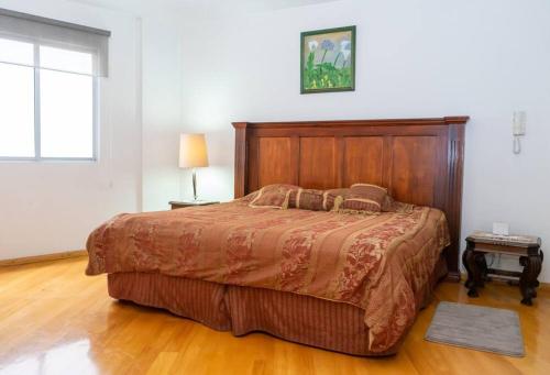 a bedroom with a large bed with a wooden headboard at Colonial Charm. Experience historic Quito. in Quito