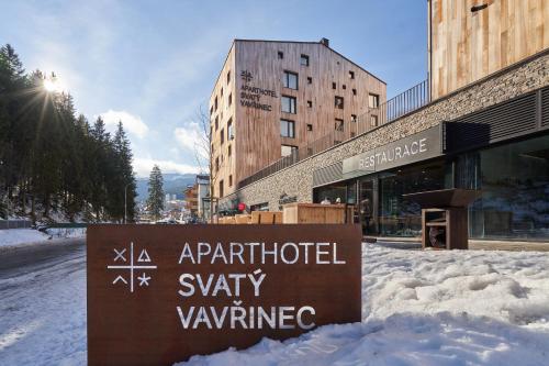 un cartel en la nieve frente a un edificio en Aparthotel Svatý Vavřinec en Pec pod Sněžkou