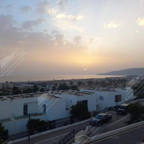 een uitzicht op een gebouw met de zonsondergang op de achtergrond bij Duplex 3 bedroom ocean view Taghazout Bay Tamourit in Taghazout