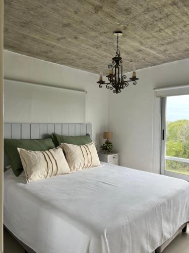 a bedroom with a large white bed with a chandelier at Pinar del Oriental in José Ignacio
