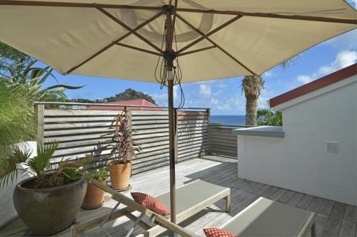 a patio with an umbrella and chairs on a deck at Villa Nagabaaja in Saint Barthelemy