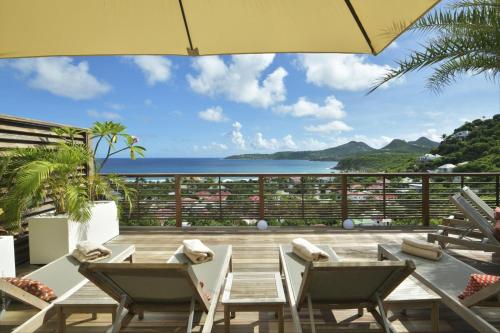 a patio with chairs and a table and an umbrella at Villa Nagabaaja in Saint Barthelemy
