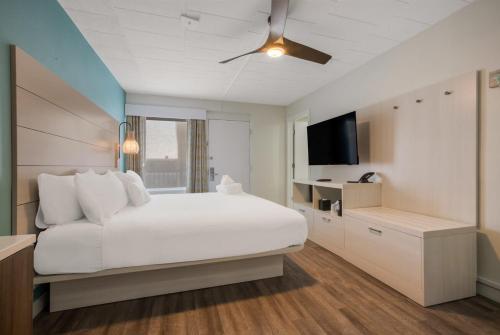 a white bedroom with a large bed and a television at Hotel Cabana Oceanfront/Boardwalk in Wildwood