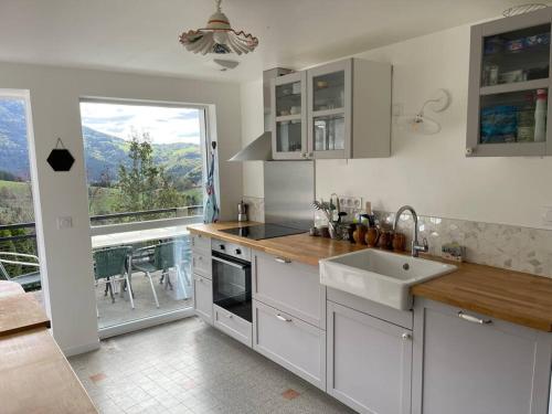 une cuisine blanche avec un évier et une fenêtre dans l'établissement Magnifique maison rénovée, 10pers, à Rencurel