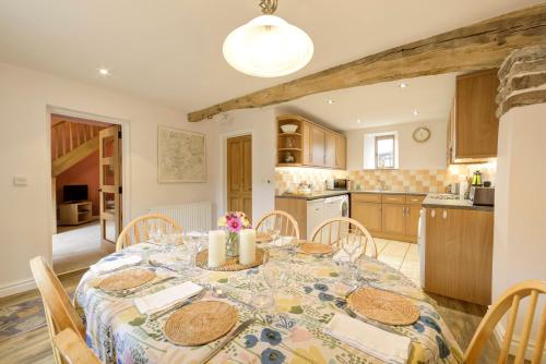 Historic cottage in the beautiful Wye Valley في Saint Briavels: مطبخ وغرفة طعام مع طاولة وكراسي