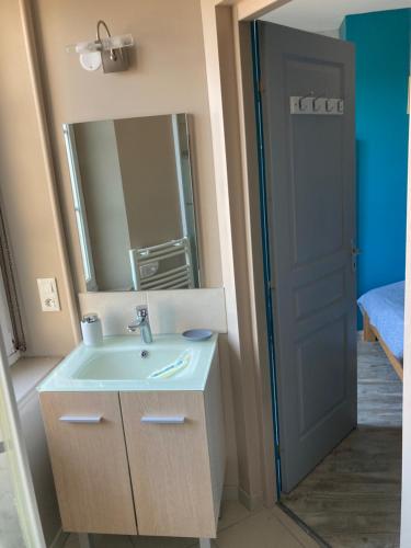uma casa de banho com um lavatório, um espelho e uma porta em LE CONTI em Corcieux