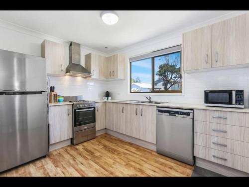 una cocina con electrodomésticos de acero inoxidable y una ventana en Gerroa Beach Family Headland Escape, en Gerroa