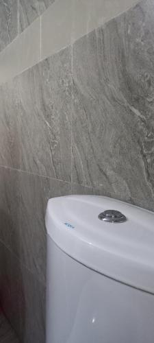 ein weißes WC im Bad mit einer Kachelwand in der Unterkunft Cozyworld Hotel in Ikeja