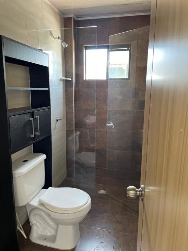 a bathroom with a toilet and a glass shower at San Jorge VVC in Villavicencio