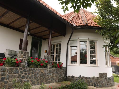 a white house with red flowers in front of it at Villa Mira in Mačkat