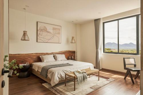 a bedroom with a bed and a chair and a window at LAKE HILL Villas in Bao Loc