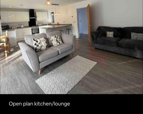 a living room with a couch and a kitchen lounge at White 3 bed bungalow with en-suite and parking in Winford