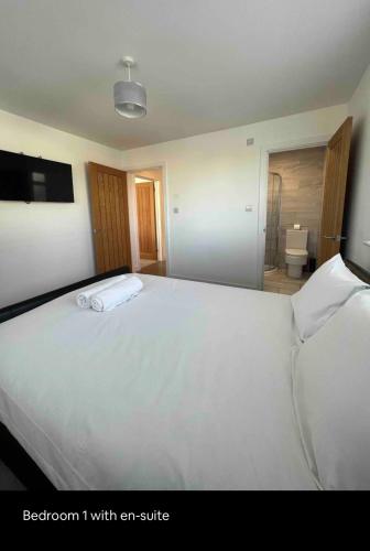 a bedroom with a large white bed with an suite at White 3 bed bungalow with en-suite and parking in Winford