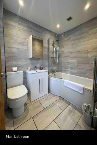 a bathroom with a tub and a toilet and a sink at White 3 bed bungalow with en-suite and parking in Winford