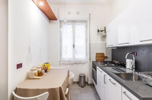ローマにあるMonteverde lovely flatのキッチン(白いキャビネット、テーブル、椅子付)