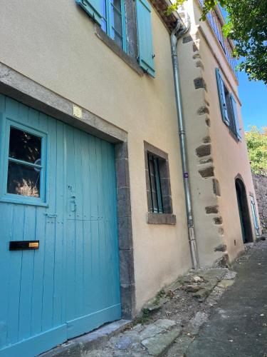 a blue garage door on the side of a building at Maison au pied du Château - L’Ange du Château in Champeix