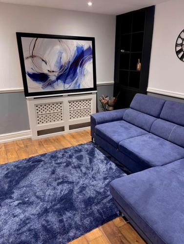 a living room with a blue couch and a large screen at Luxury 3 bedroom house -Private parking, sleeps 6, & featuring en-suite master bedroom in Birmingham