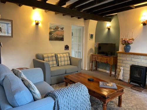 a living room with two couches and a fireplace at Gingerbread Cottage in Chideock