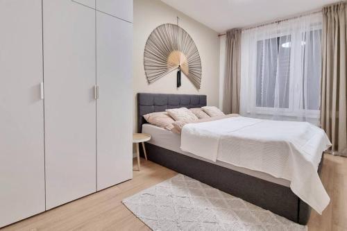 10 Minutes to City: Cozy Urban Apartment Stay في براتيسلافا: غرفة نوم بيضاء مع سرير كبير ونافذة