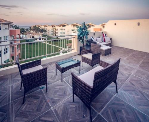 a balcony with chairs and tables and a couch at Paradise Coast Penthouse - Luxury in Paradise in Isabela