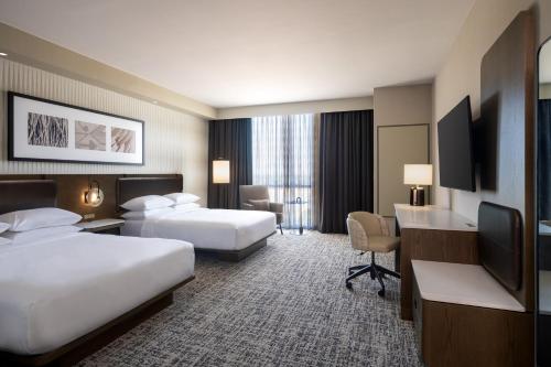 ウィチタフォールズにあるDelta Hotels by Marriott Wichita Falls Convention Centerのベッド2台とデスクが備わるホテルルームです。