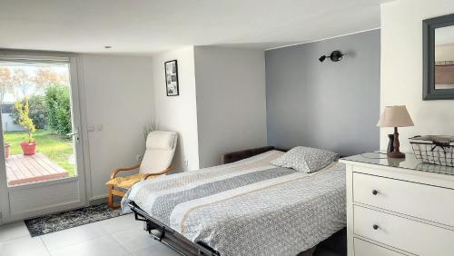 ein Schlafzimmer mit einem Bett, einem Stuhl und einem Fenster in der Unterkunft Charmant Studio Cosy in Plaisance-du-Touch