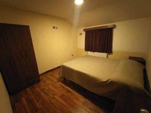 1 dormitorio con cama y ventana en Cabañas Angamos en Punta Arenas