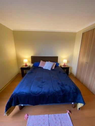 1 dormitorio con 1 cama azul grande y 2 lámparas en Departamento Bellas Artes en Santiago