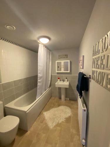 a bathroom with a tub and a toilet and a sink at Beautiful 1 -Bed Apartment in Ferry Village/Renfrew in Renfrew