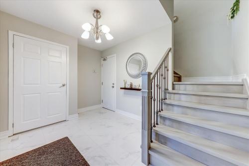 a white hallway with stairs and a white door at Stunning 7 Br RougeView Home with 2 Kitchens, 5 Bathrooms, Amazing Backyard & 8-Car Parking in Toronto