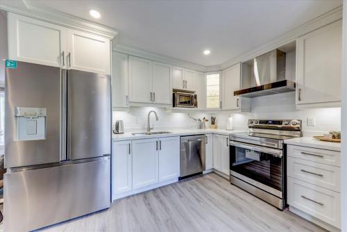 a kitchen with white cabinets and a stainless steel refrigerator at Stunning 7 Br RougeView Home with 2 Kitchens, 5 Bathrooms, Amazing Backyard & 8-Car Parking in Toronto