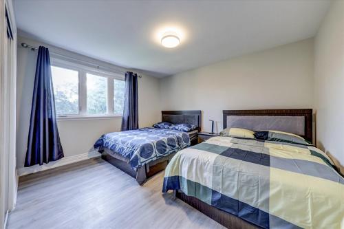 a bedroom with two beds and a window at Stunning 7 Br RougeView Home with 2 Kitchens, 5 Bathrooms, Amazing Backyard & 8-Car Parking in Toronto