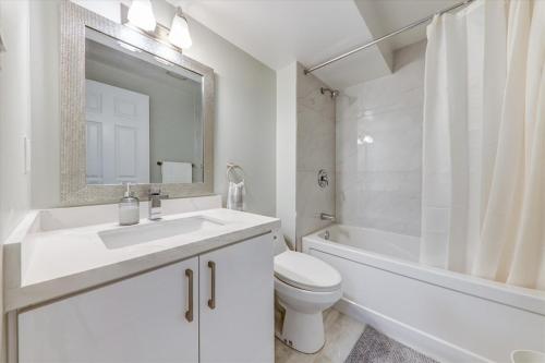 Stunning 7 Br House with 2-Kitchen, 5-Washroom & Amazing Backyard في تورونتو: حمام أبيض مع حوض ومرحاض وحوض استحمام