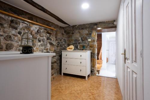 a kitchen with a white dresser and a stone wall at Elantxobe Centre in Elanchove
