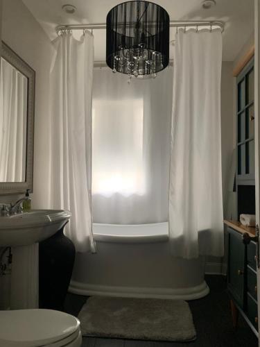 a bathroom with a tub and a toilet and a chandelier at Oak Park Beauties - Tree Lined Streets - Walkable in Oak Park