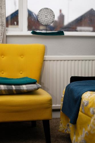 a yellow chair next to a window with a fan at Harmony Haven - Harmony Suite in Nottingham