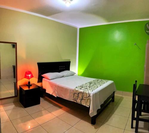 um quarto verde com uma cama e uma parede verde em Hostal Los Helechos Tarapoto em Tarapoto