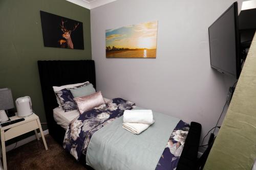a small bedroom with a bed and a television at Harmony Haven - Serenity Suite in Nottingham