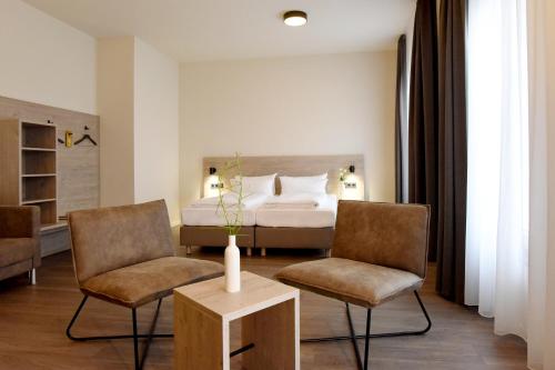 ein Hotelzimmer mit einem Bett und zwei Stühlen in der Unterkunft DiMas Hotel Ettenheim - Rust in Ettenheim