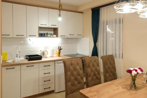 a kitchen with white cabinets and a table and chairs at Villa Zagorka and mountain houses A, M, D in Kopaonik