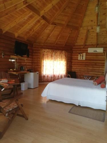 1 dormitorio con 1 cama blanca en una habitación de madera en Complejo Siyabona en Trapiche