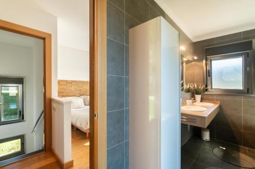 ein Badezimmer mit einem Waschbecken und ein Schlafzimmer mit einem Bett in der Unterkunft helloasturias, Casa en Llanes con piscina, jardín, cerca de la playa. in Llanes