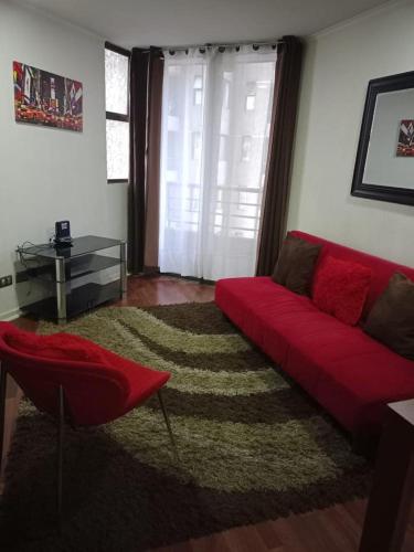 uma sala de estar com um sofá vermelho e um tapete em DepartamentosRuiz em Santiago