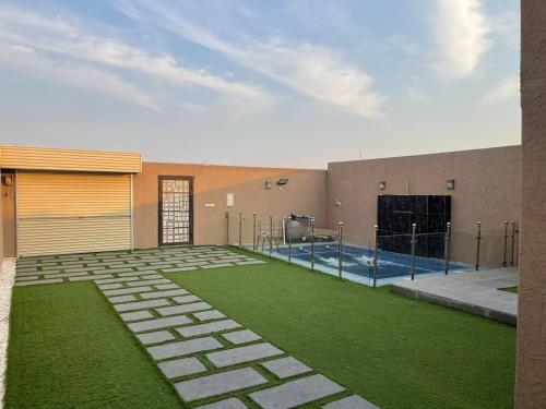 a building with a pool and a yard with grass at شاليهات الأحلام in Rayyis