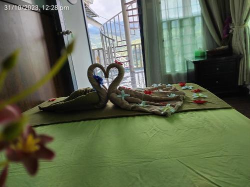2 cygnes de serviettes assises au-dessus d'un lit dans l'établissement Highland Homestay Kundasang, à Ranau