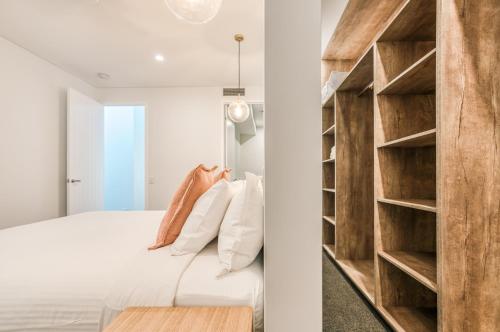 a bedroom with a white bed and wooden shelves at Essence Peregian Beach Resort - Lily 4 Bedroom Luxury Home with Private Pool in Peregian Beach