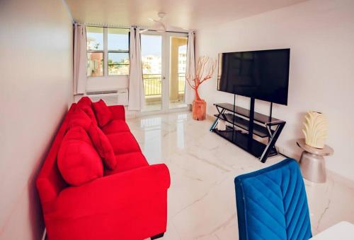 Paradise Coast PR - Condo في إيزابيلا: غرفة معيشة مع أريكة حمراء وتلفزيون بشاشة مسطحة