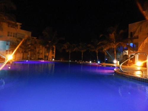 a large swimming pool at night with blue lights at Paradise Coast PR - Condo in Isabela