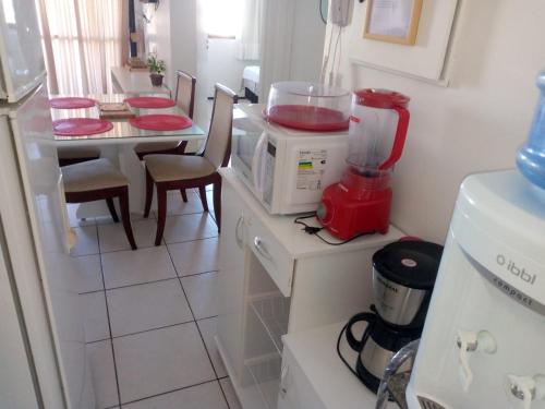 Il comprend une cuisine équipée d'un four micro-ondes et d'une table avec des chaises. dans l'établissement Apartamento em Fortaleza, Abolição Mucuripe, à Fortaleza